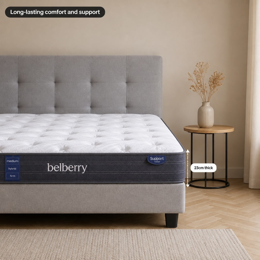 Belberry Support mattress with a white tufted mattress and a gray upholstered headboard in a softly styled bedroom. A small round side table with a vase of dried stems sits beside the bed. Also showing thickness of mattress